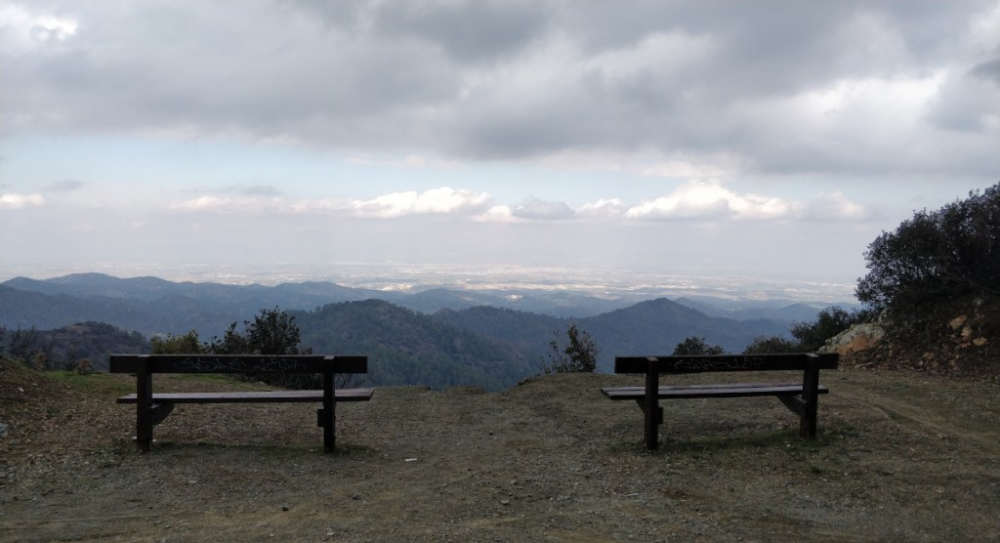 A serene seating area with comfortable chairs overlooking a scenic mountain view, 
            framed by green trees and an expansive horizon, inviting relaxation and tranquility